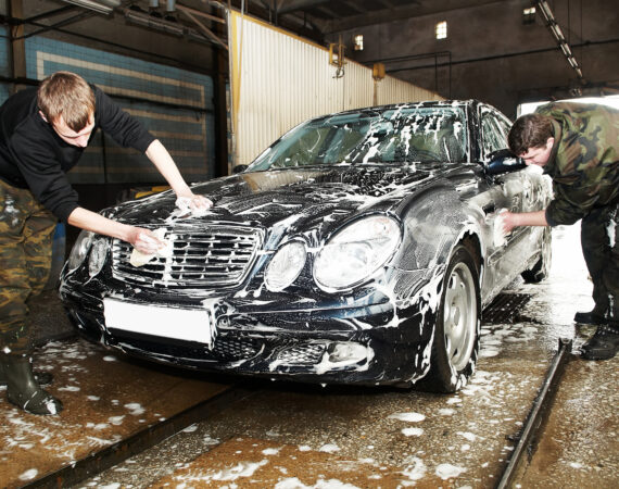 Manual car washing cleaning with foam and water at service station